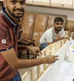 Team members assembling the large wing over workshop blueprints